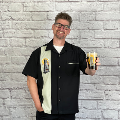 This loose, comfortable, and airy "Enchanted Tiki Gardens" PopCheck Single Panel Bowling Shirt in Black/Light Sage Green is great for all you tiki lovers out there! It features an embroidered, "Kahona" tiki from the Enchanted Tiki Gardens on a single sage green panel on a black polyester shirt and features contrast piping on the breast pocket. Custom metal tiki buttons complete this one-of-a-kind tiki shirt! 
